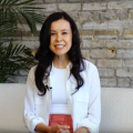 Screenshot of Kate Kamo McHugh, sitting on a white couch during a video interview.