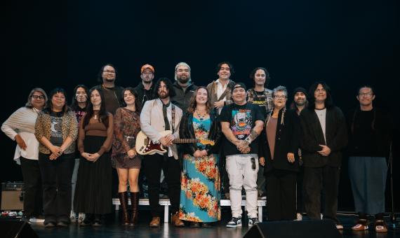 Participants of the Soundin Rez programs (young artists) lined up in a group on stage for a photo.