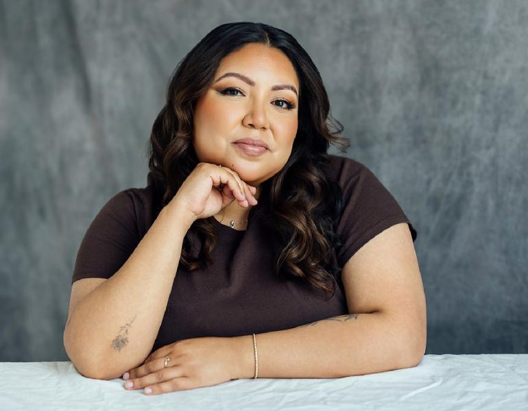 Joelle's headshot with her hand to her shin in front of a grey background.