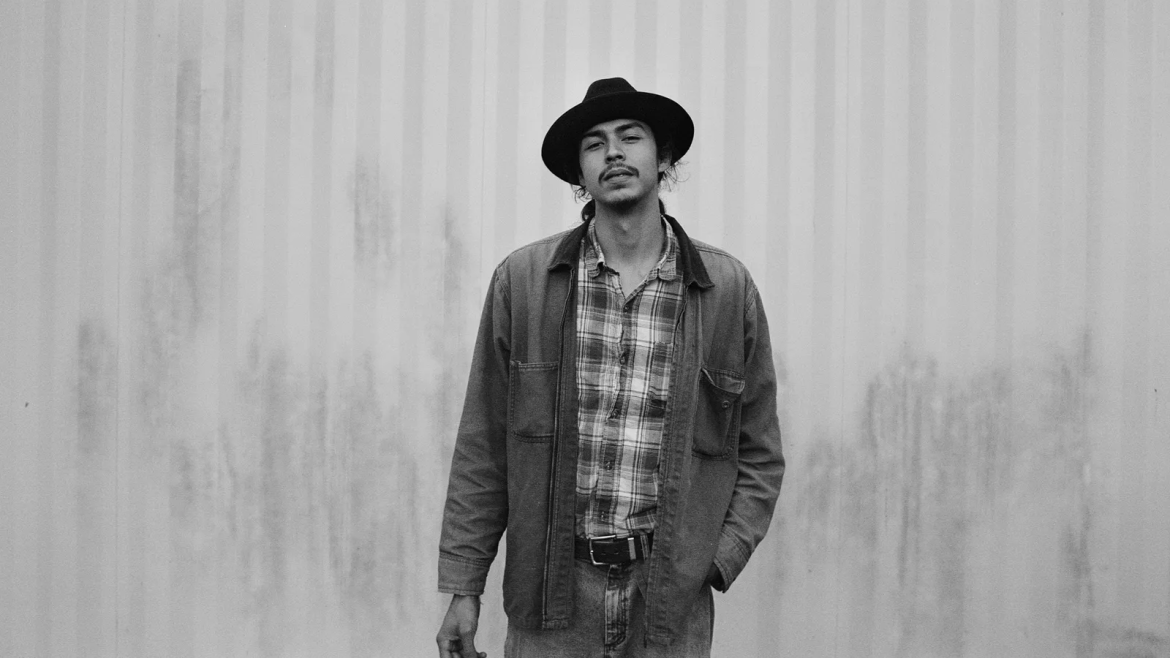 JD Crosstown standing in front of an aluminium wall in black and white.