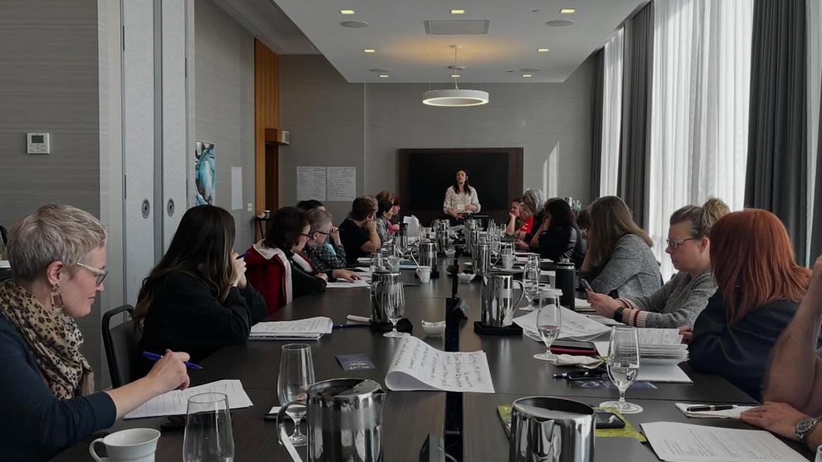 Carrie Libling leading a workshop in a large board room.