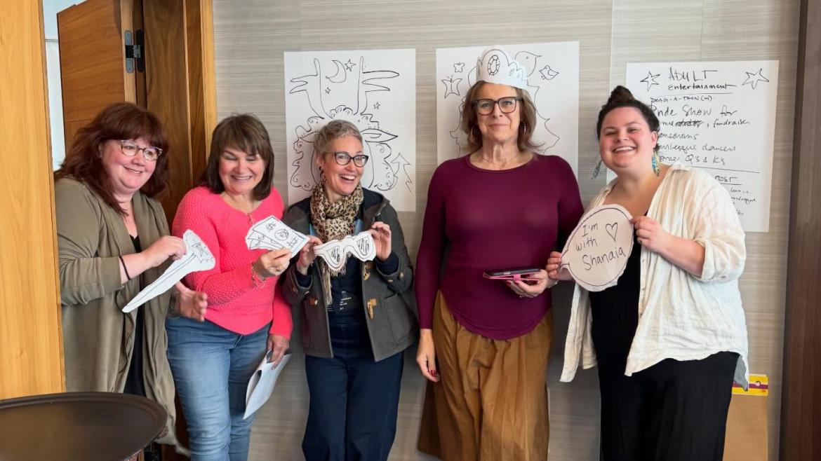 A group of workshop attendees smiling and holding up drawings.