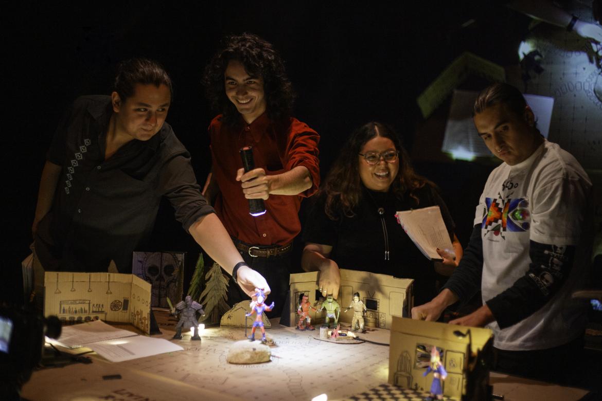 A smiling group of people around a mini stage set holding flashing lights and papers.