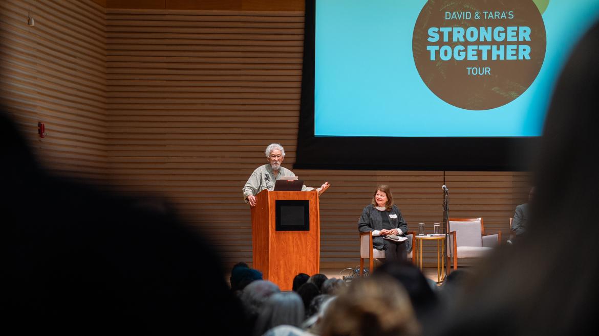 David Suzuki speaking on stage at a podium.
